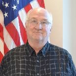 Man standing in front of flag