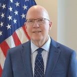 Man standing in front of flag