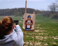 Person Aiming a Gun at a Target in a Field